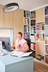 Anne werkt aan haar bureau in een thuiskantoor op maat met wandvullende boekenkasten en geïntegreerde opbergruimte