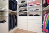 Op maat gemaakte dressing in een U-vorm met planken voor opgevouwen kleding en hangrails voor jassen en truien.
