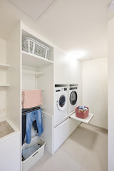 Wasruimte op maat met wasmachine, droger, wasmand en opbergruimte voor kleding en accessoires.