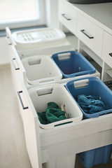 Panier de rangement pour linge sale dans un meuble de buanderie, avec différents compartiments.