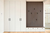 Meuble d’entrée sur mesure avec rangements fermés et banc intégré, habillé de finitions bois et blanc.