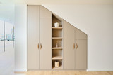 Meuble de vestiaire d'entrée beige sous pente et sur mesure avec placards et étagères à Wavre