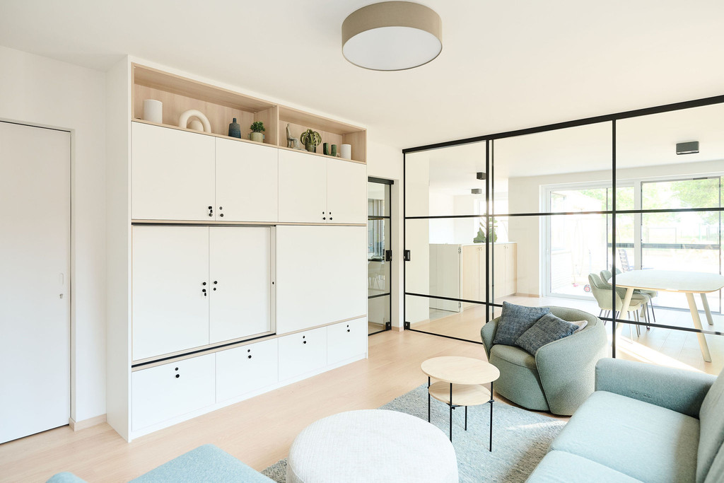 Salon avec meuble blanc sur mesure autour de la télévision et cloison vitrée vers la salle à manger