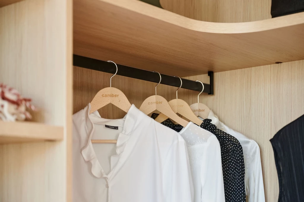 Tringle noire suspendue avec vêtements accrochés dans une penderie en bois sur mesure.
