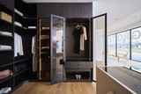 Dressing sur mesure avec portes miroir, penderie et tiroirs en bois foncé dans un showroom