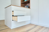 Îlot de dressing blanc avec tiroirs ouverts sur parquet dans un dressing moderne