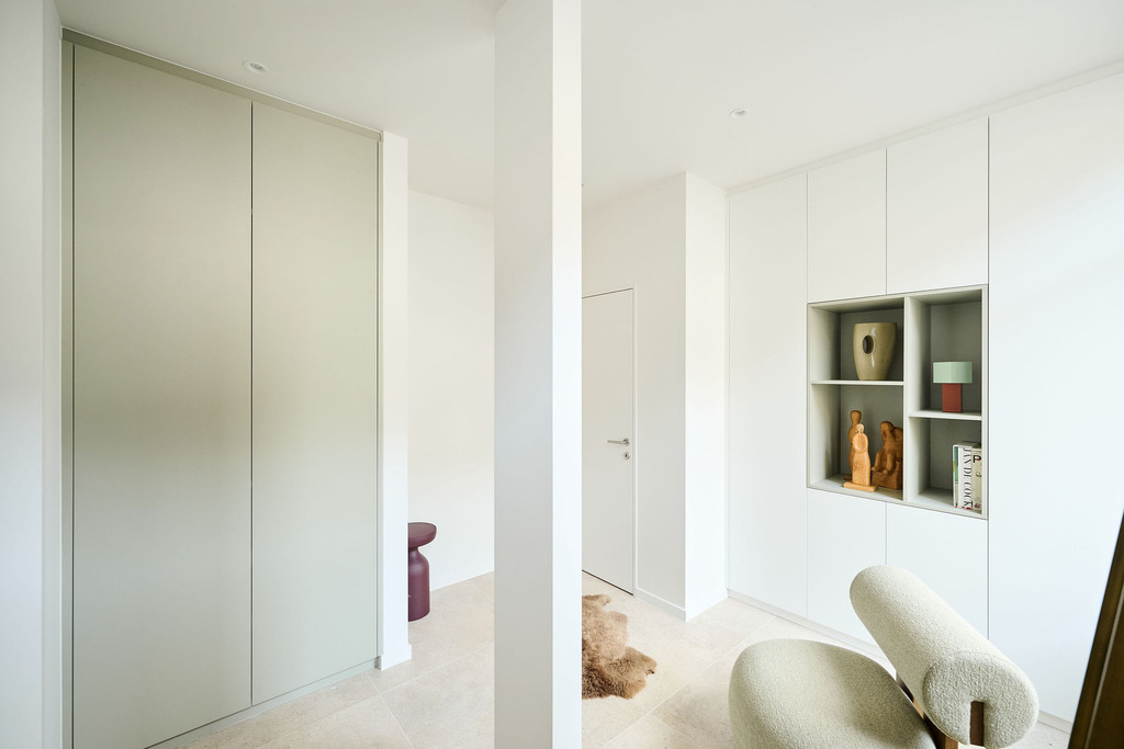 Hall d’entrée lumineux avec deux armoires blanches sur mesure dont une avec niches ouvertes et une encastrée fermée