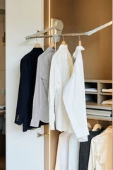 Detail van een kledingkast op maat met uitschuifbare kledinglift, hangruimte voor hemden en jassen en geïntegreerde verlichting