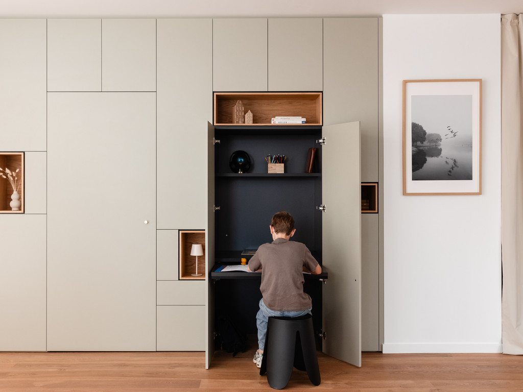 Bibliothèque sur mesure avec bureau escamotable dissimulé derrière des portes, offrant un espace dédié aux devoirs, aux études ou au télétravail tout en restant invisible une fois refermé