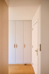 Placard sur mesure intégré avec portes blanches et poignées en bois dans une chambre lumineuse