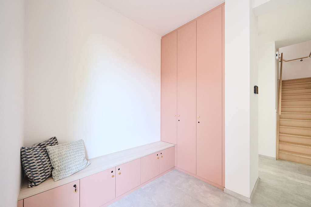 Hall avec armoires sur mesure roses, banc avec coussins et rangements hauts