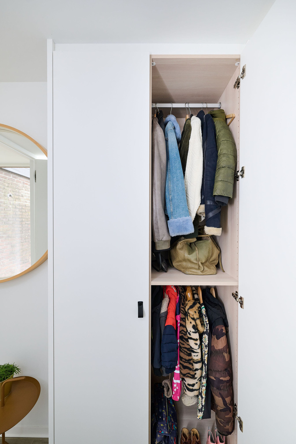 Armoire d'entrée fermée sur mesure avec étagères et porte pour manteaux, disposée dans un hall clair et moderne.