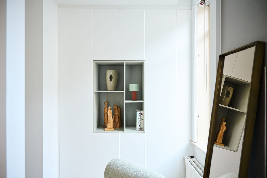 Armoire blanche sur mesure avec niches centrales ouvertes dans une pièce lumineuse avec radiateur et miroir