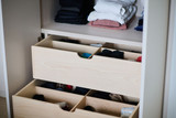 Tiroirs ouverts avec vêtements pliés et rangements compartimentés dans une armoire sur mesure
