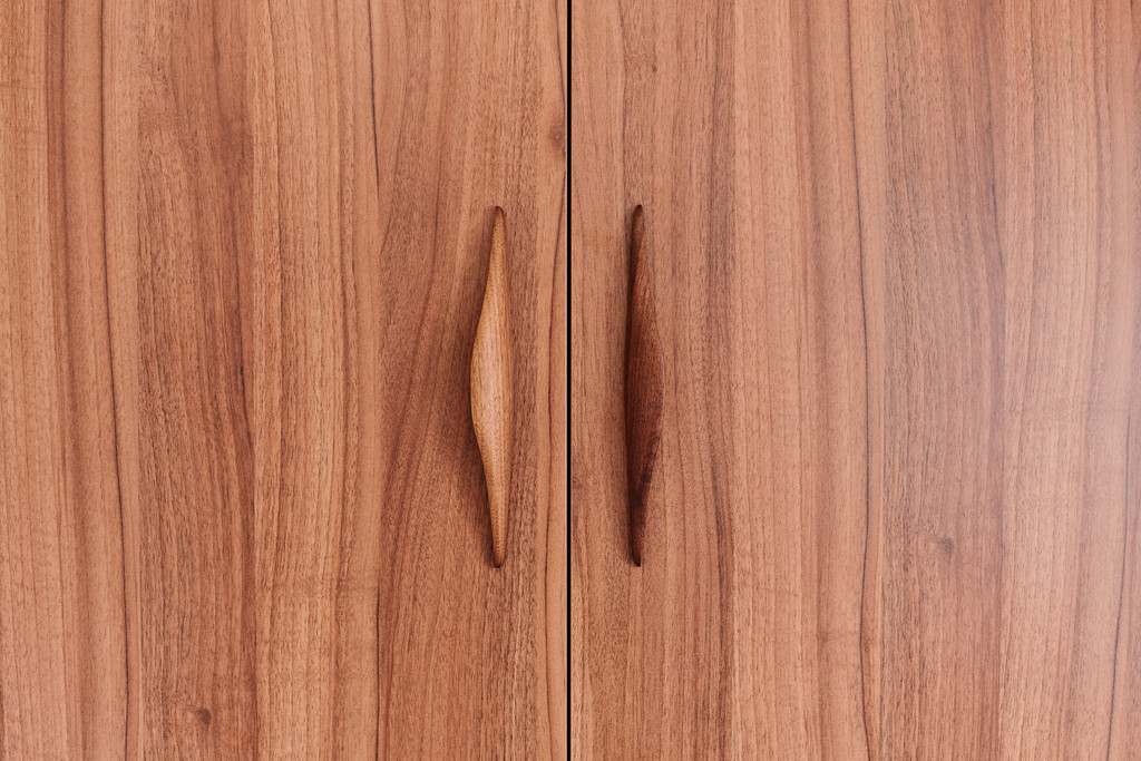Portes d’armoire en bois avec poignées sculptées intégrées pour une finition naturelle et élégante.