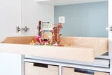 Rangement sur mesure avec tiroir de stockage pour jouets, maison de poupées en plastique coloré à l'intérieur.