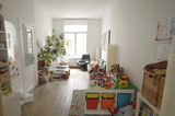 Salon familial avant transformation, avec jouets pour enfants, plantes et coin bureau