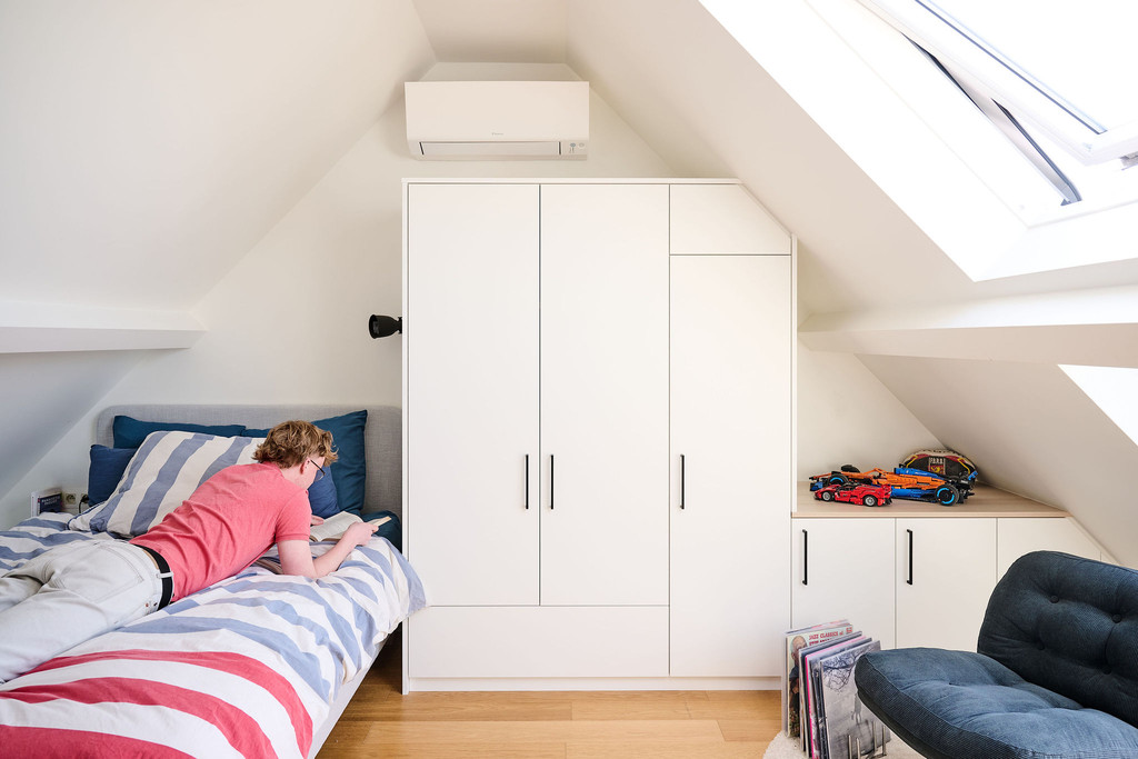 Placard sur mesure avec portes et rangements sous pente entre deux lits dans une chambre d’enfant