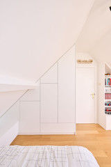 Placard sur mesure intégré sous pente avec portes blanches et rangements intégrés