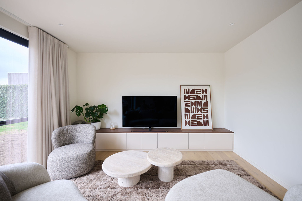 Meuble TV sur mesure avec armoires basses et plateau foncé dans un salon moderne aux tons beiges