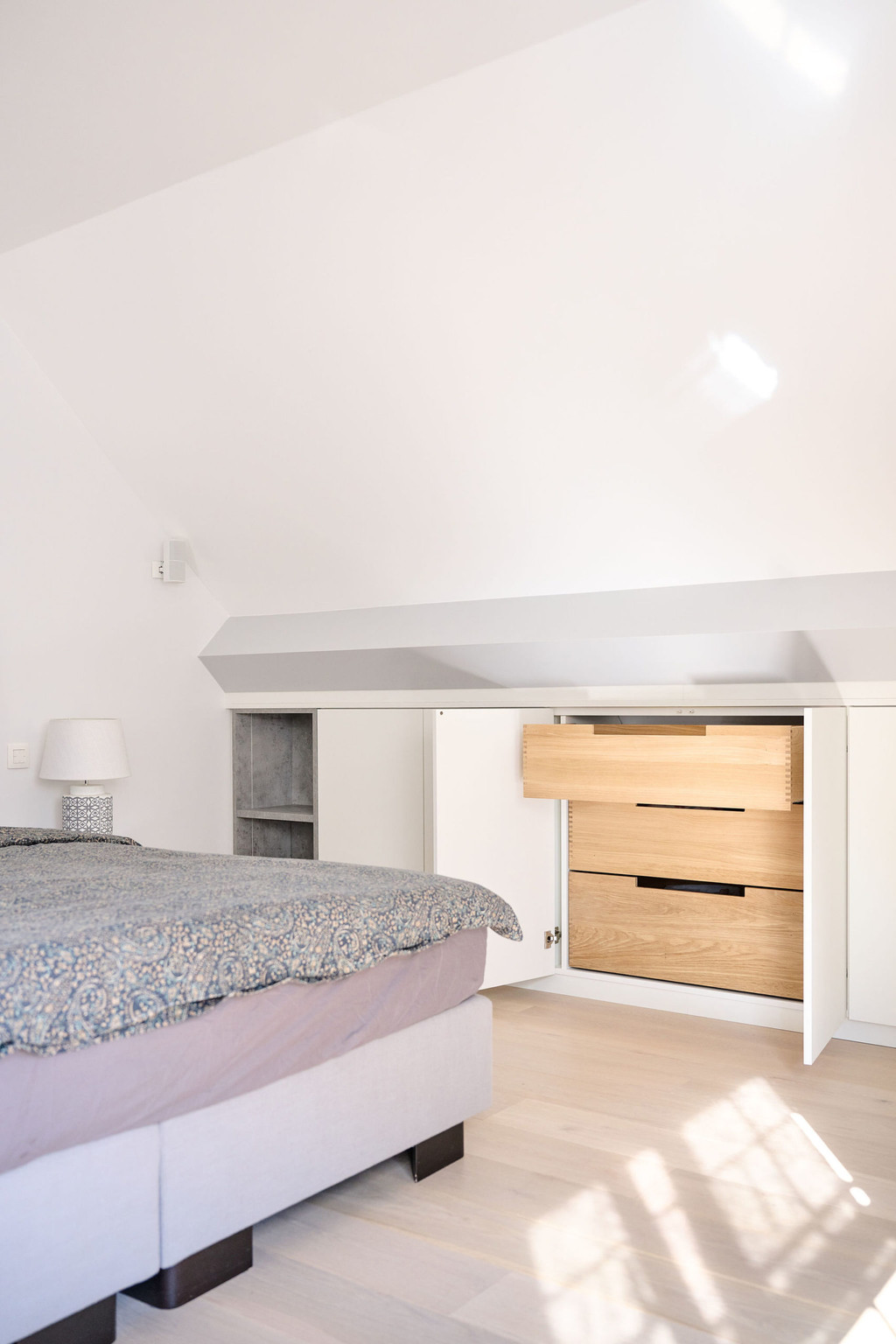 Meuble blanc fermé avec tiroirs en bois dans la chambre à coucher de Morgane