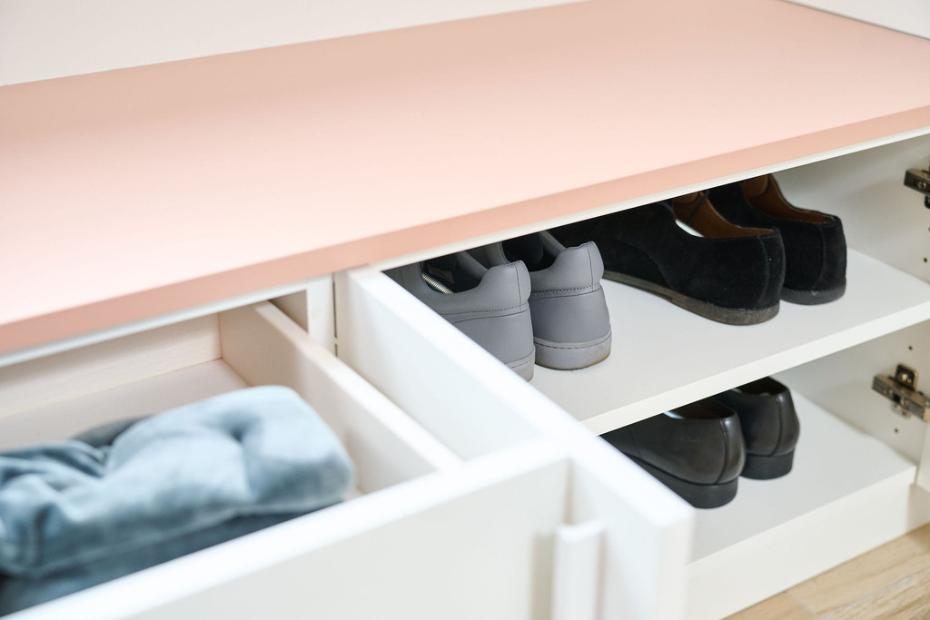 Dressing en L sur mesure avec tiroirs blancs et rangement pour chaussures, avec des compartiments pour organiser les articles.
