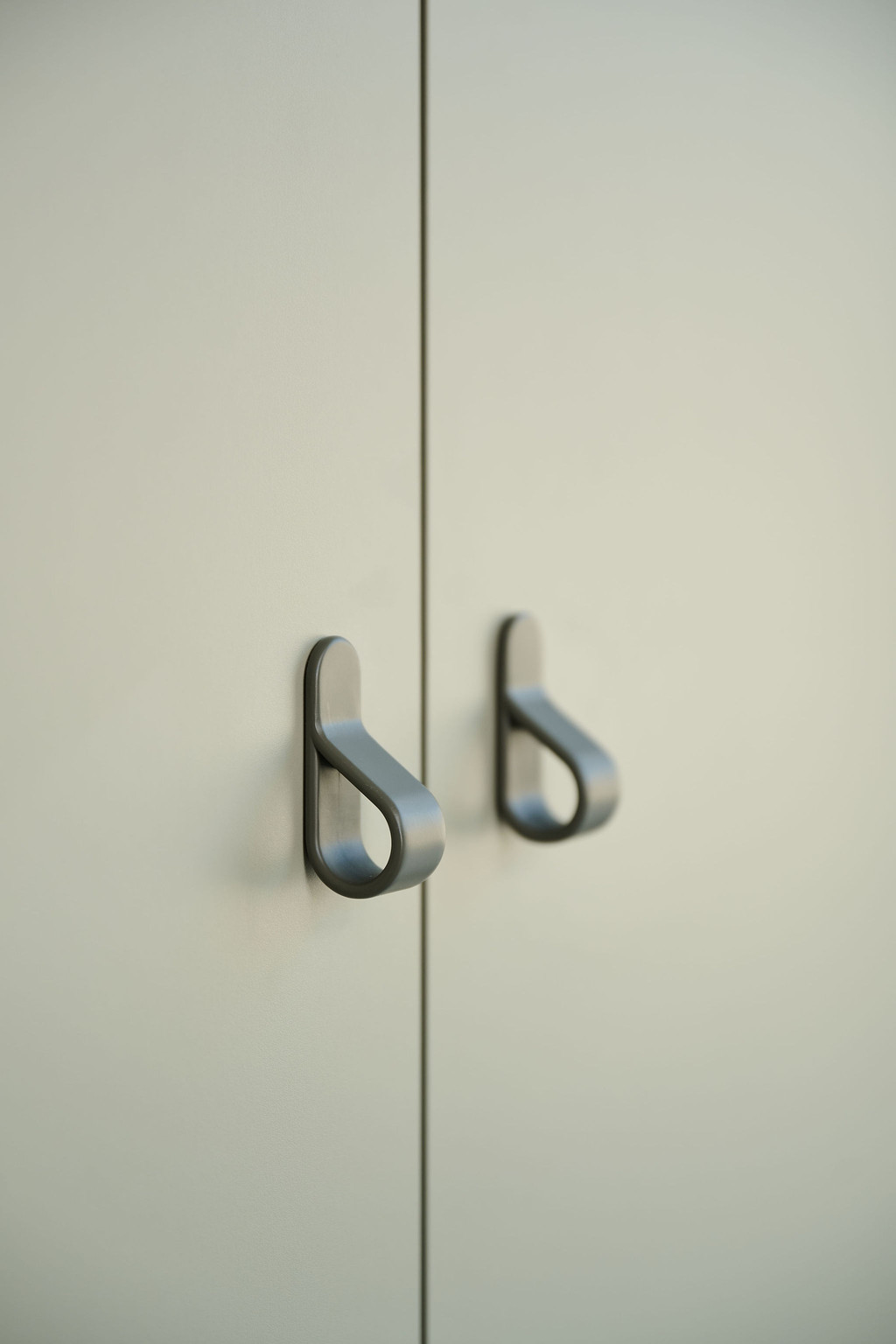 Détail des placards Camber sur mesure dans la buanderie, avec poignées modernes sur portes claires, intégrées dans un design épuré et fonctionnel