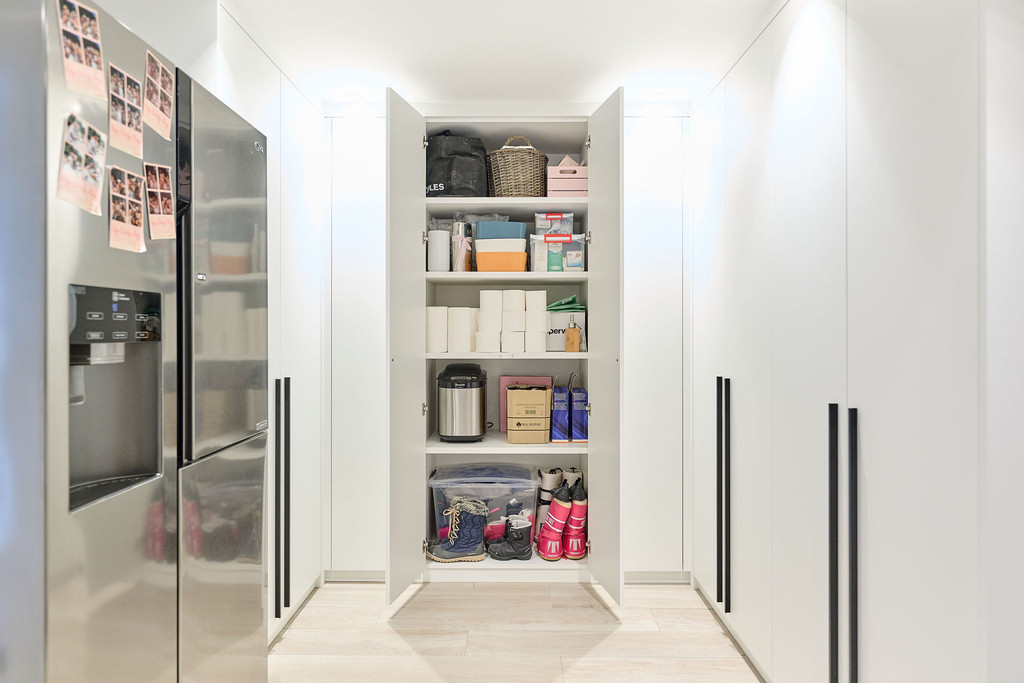 Armoire blanche sur mesure pour buanderie avec étagères organisées contenant divers produits de nettoyage et accessoires.