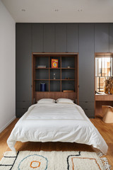 Lit ouvert dans une chambre avec armoire sur mesure noire et niche bibliothèque en bois foncé