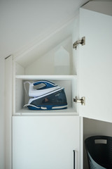 Meuble de buanderie sur mesure avec un espace de rangement pour un fer à repasser et autres accessoires ménagers.