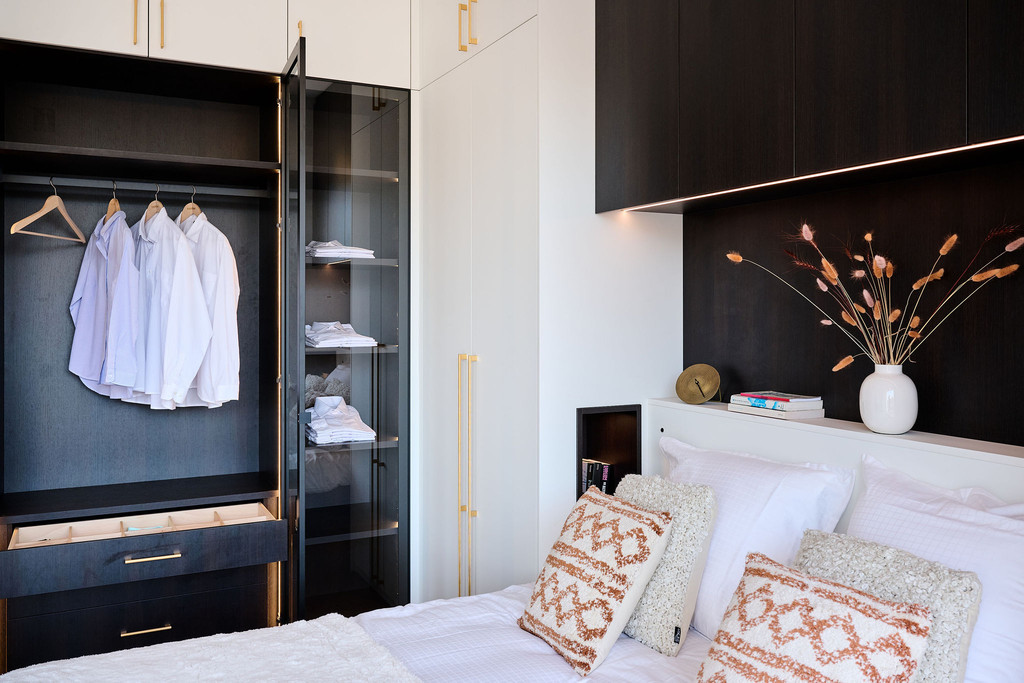 Armoire dans la chambre à coucher avec penderie et étagères derrière une porte en verre
