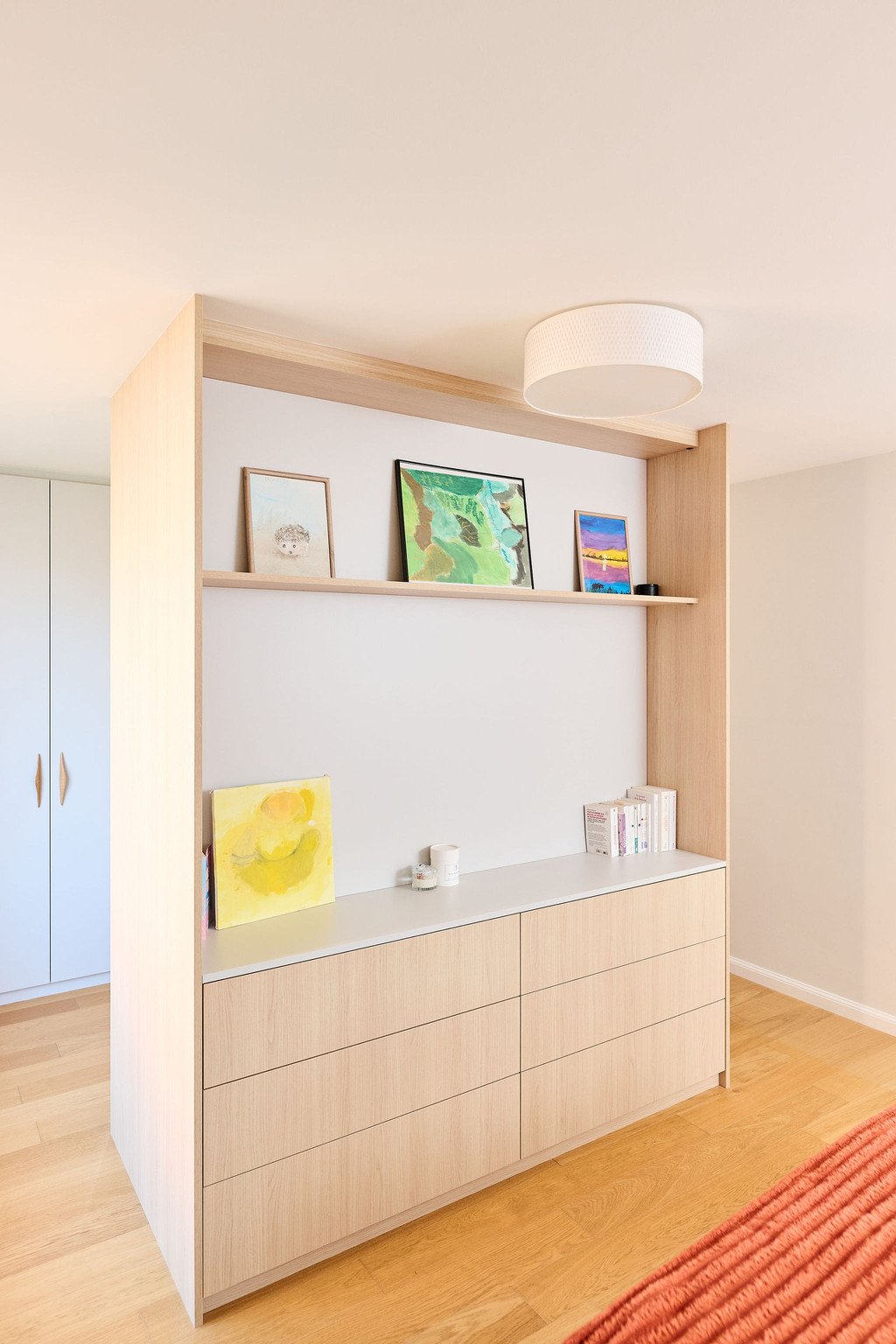 Placard sur mesure utilisé comme séparateur de pièce avec niche ouverte, rangements fermés et finition bois dans une chambre