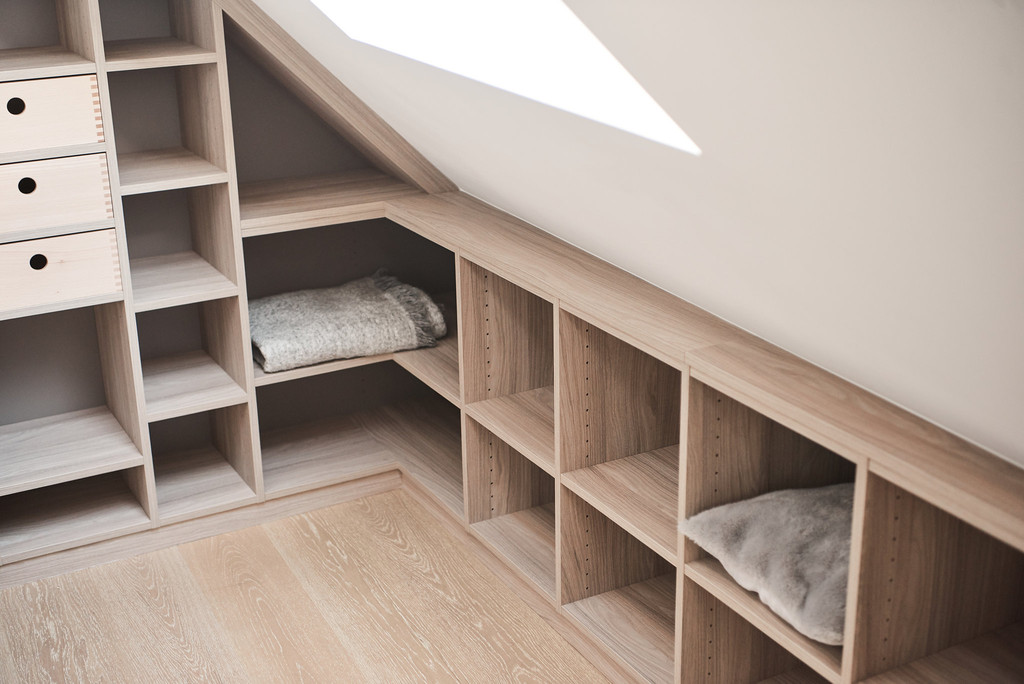 Rangement sous toit avec étagères ouvertes, utilisant l'espace de manière optimisée pour les couvertures et autres objets.