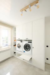 Colonne sur mesure blanche avec lave-linge et sèche-linge intégrés dans une buanderie lumineuse