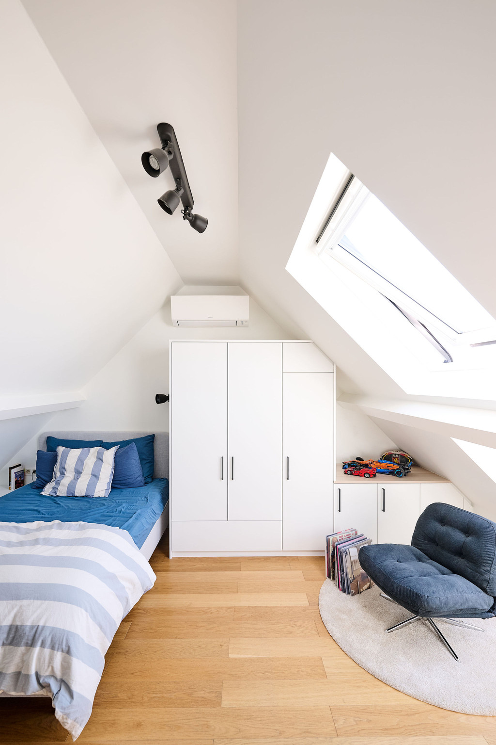 Placard sur mesure avec portes et lit sous pente dans une chambre d’enfant lumineuse avec fenêtre de toit