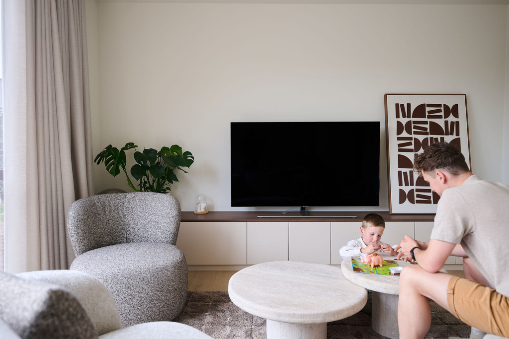 Enfant et adulte à une table basse dans un salon lumineux avec meuble TV sur mesure