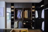 Dressing sur mesure avec penderie, tiroirs et niches ouvertes en bois foncé dans un showroom