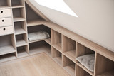 Rangement sous toit avec étagères ouvertes, utilisant l'espace de manière optimisée pour les couvertures et autres objets.