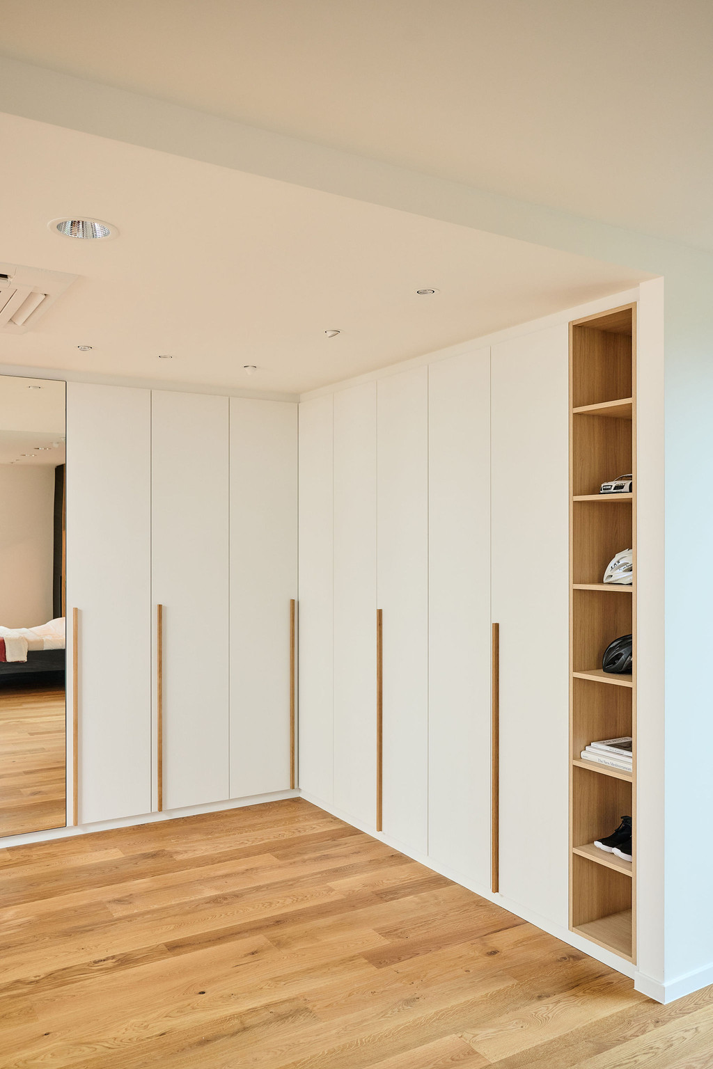 Gesloten dressing in L-vorm met houten open nissen en spiegeldeur
