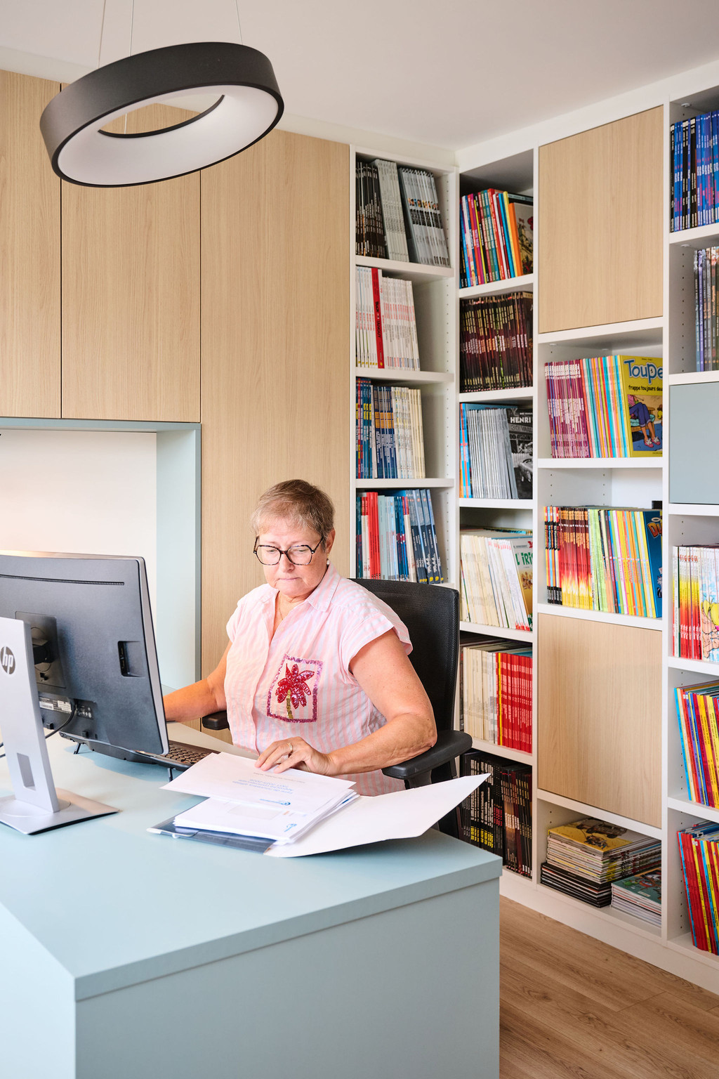 Anne werkt aan haar bureau in een thuiskantoor op maat met wandvullende boekenkasten en geïntegreerde opbergruimte