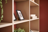 Opklapbed met op maat gemaakte kast met open planken en decoratieve items in een moderne slaapkamer.