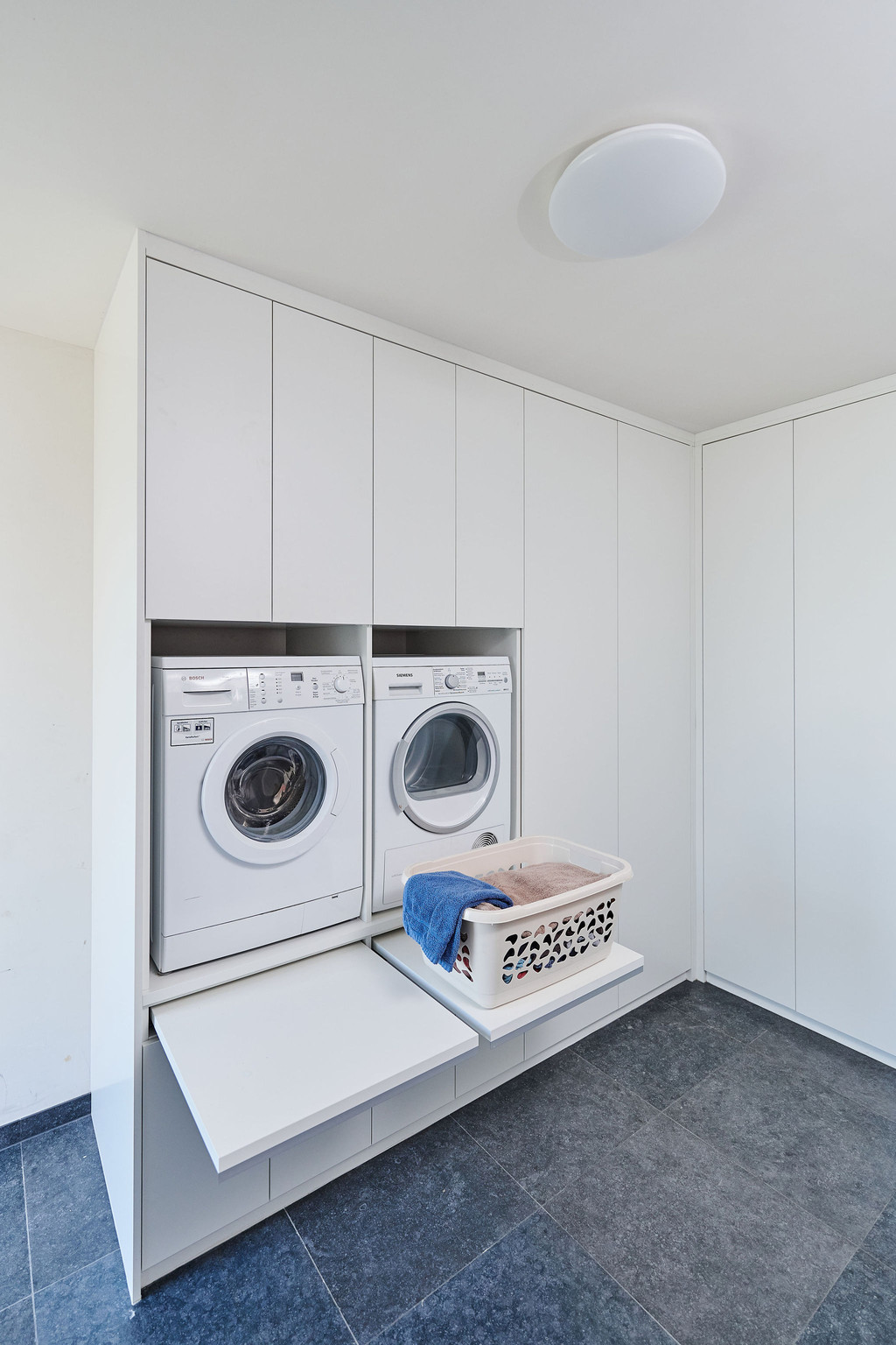 Wasruimte op maat met wasmachine, droger en opbergruimte voor wasmanden en andere benodigdheden.