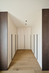Dressing sur mesure en U avec portes blanches épurées et longues poignées noires, offrant une organisation optimale dans un espace symétrique, réalisé par Camber