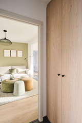 Armoire vestiaire en bois sur mesure avec poignées noires dans une entrée avec vue sur un salon chaleureux