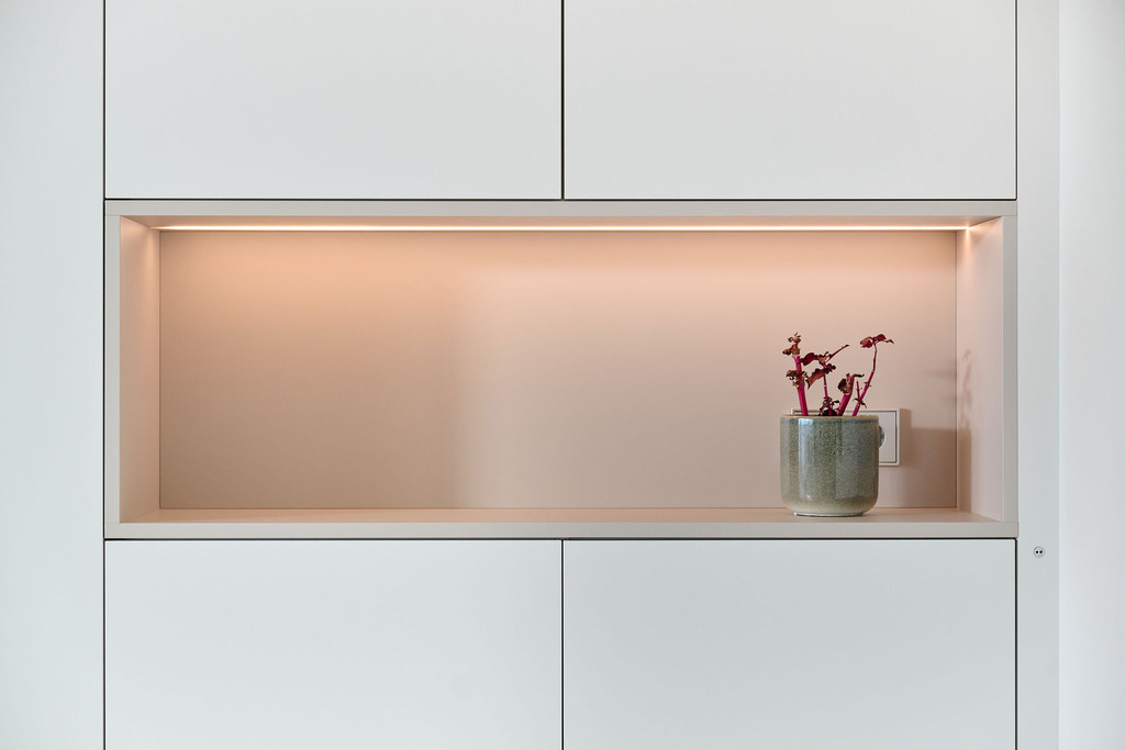 Op maat gemaakte kast met verlichte niche en plant in een moderne woonkamer.