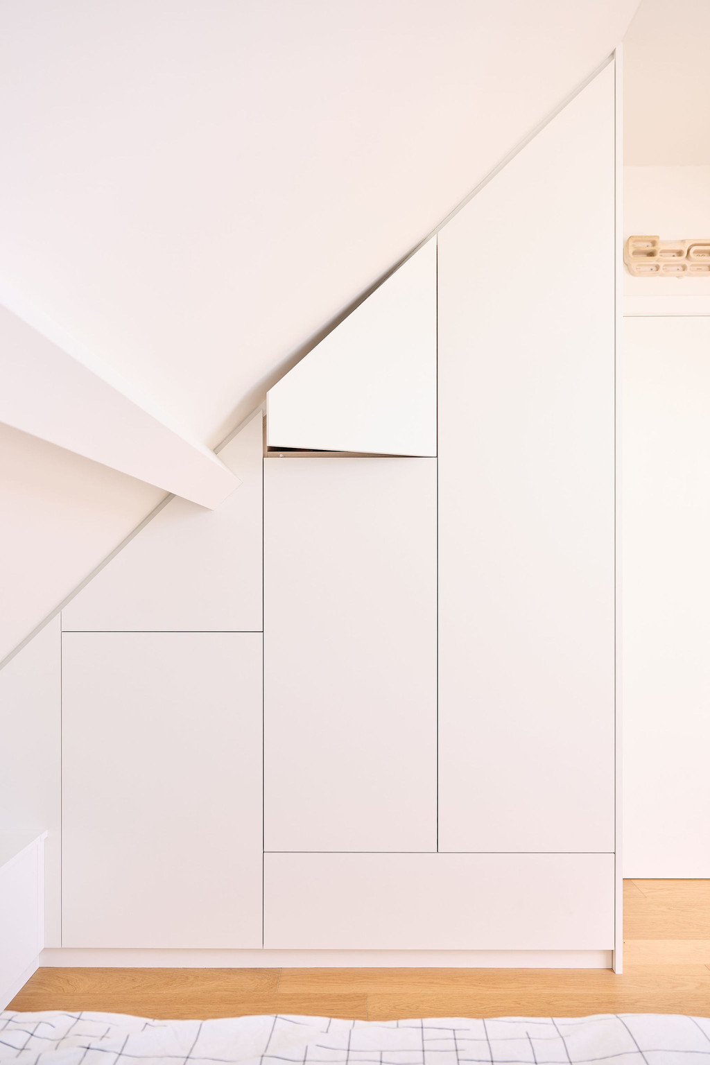 Placard sur mesure encastré sous pente avec portes minimalistes dans une chambre d’enfant