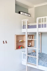 Chambre d'enfant avec lit superposé et étagère murale intégrée pour rangement.