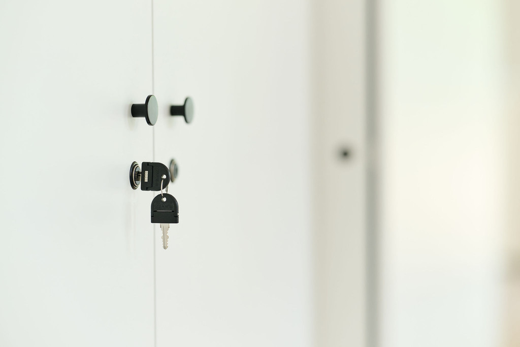 Détail d’un meuble blanc sur mesure avec boutons noirs et serrure à clé