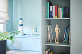 Detail van open kastdeel in blauw bureau met boeken houten figuurtje en maritieme decoratie