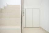 Witte ingemaakte kast onder een trap met strakke afwerking en greeploze deuren, optimaal gebruik van de ruimte onder de trap.